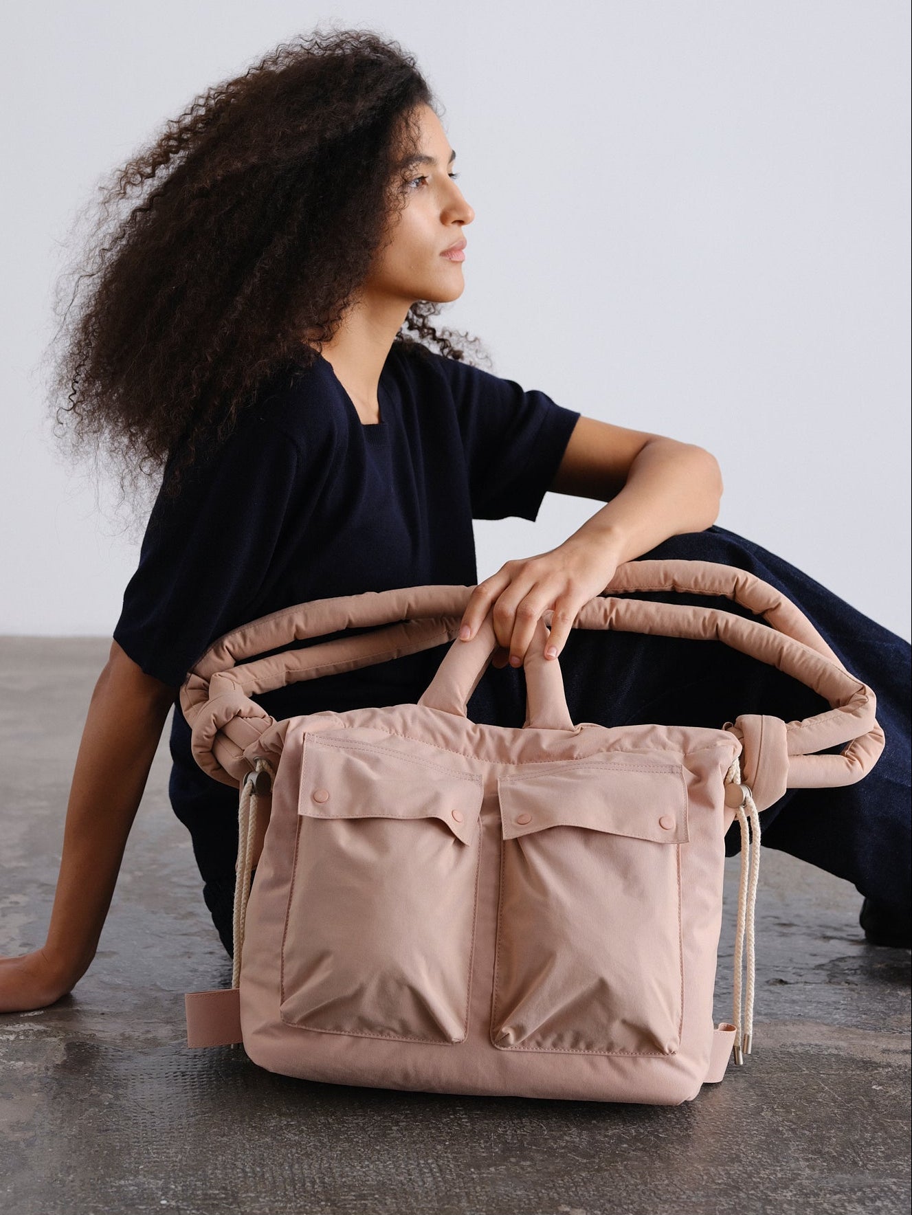 ÖLEND Rain Ona Dust Pink en rosa empolvado, con modelo sentada y bolso sobre las piernas